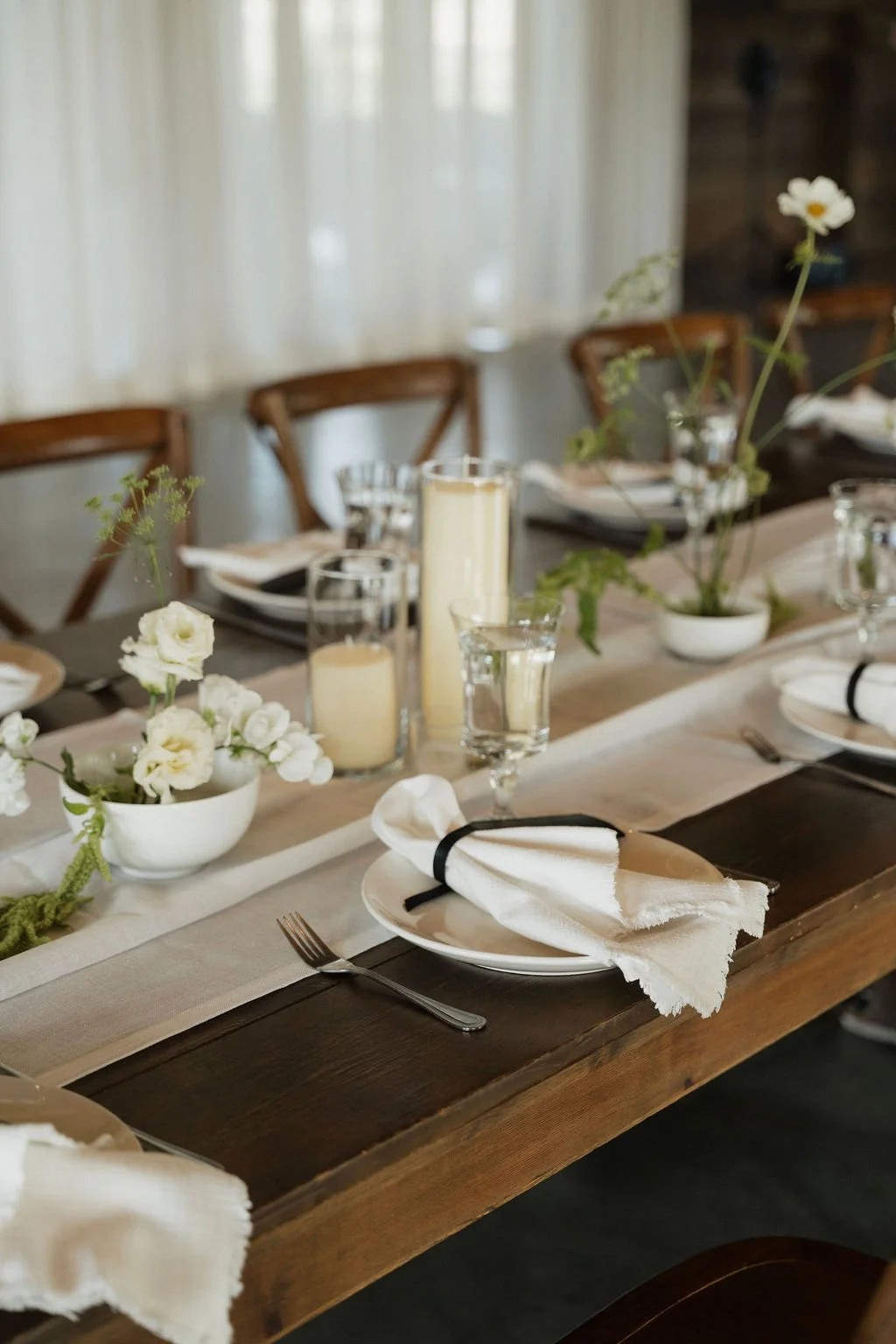 a detail shot of the white napkins, white runners candles and the ikebana florals on the tables 