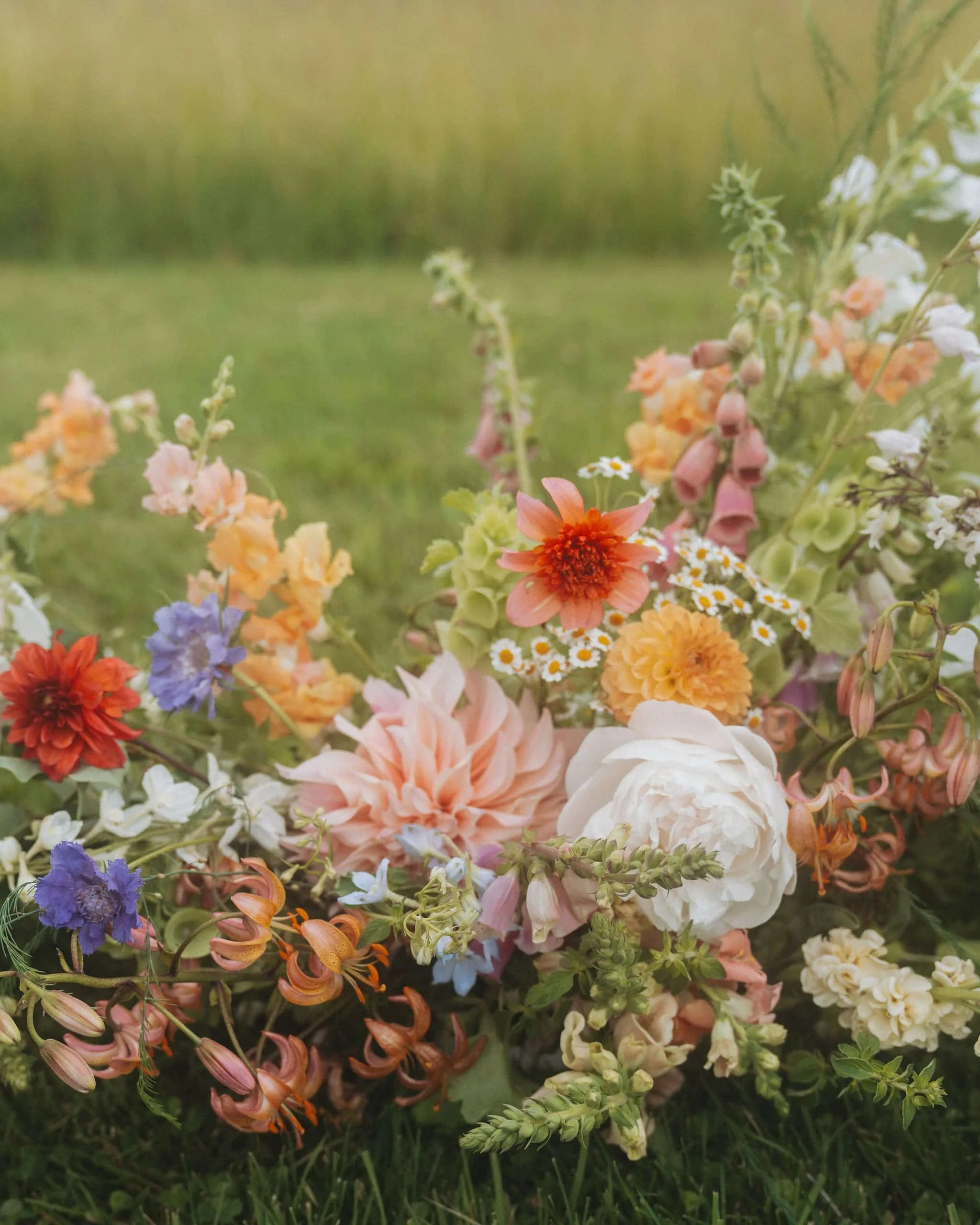 bozeman montana florists arrangements using cafe dahlias, chamomile feverfew, snapdragons, cafe au lait dahlias, bells of ireland and martagon lilies and peonies in a wedding meadow
