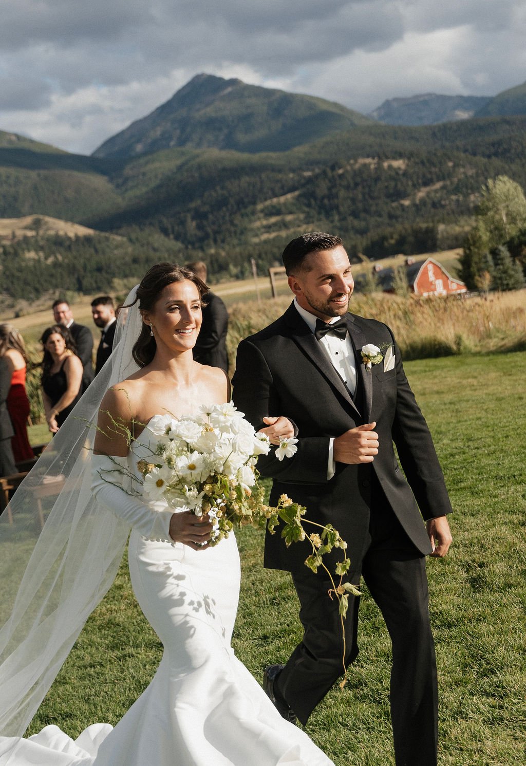 bride and groom so happy as they walk away from the ceremony with her cascading bouquet in her hand
