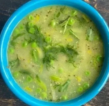 bowl of spring soup with peas, asparagus, herbs, and mustard seeds