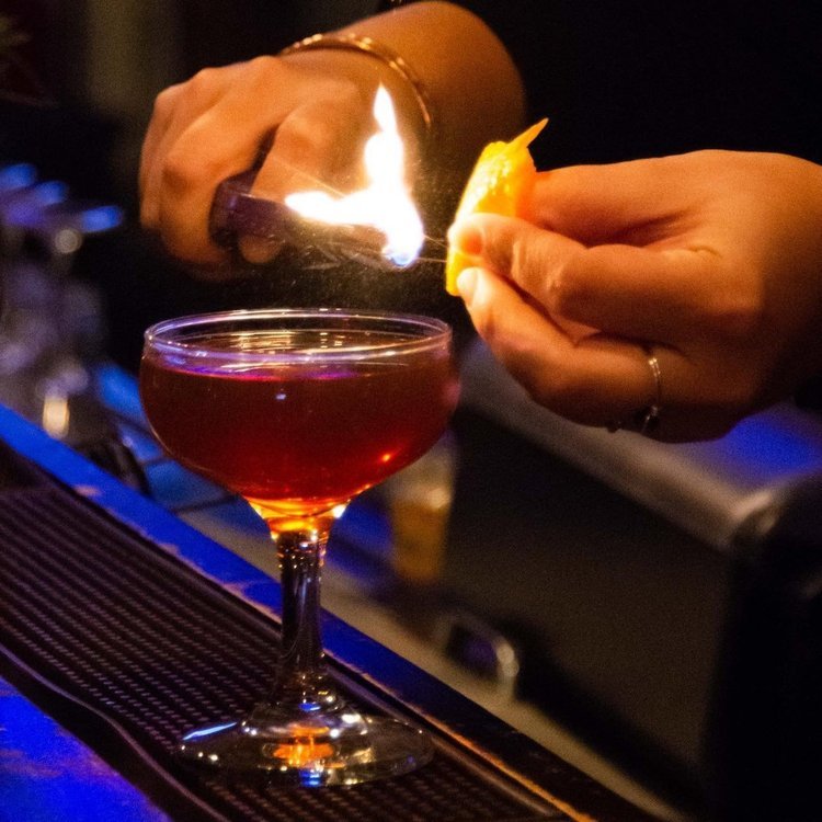 A bartender uses a lighter to garnish a drink at Timekeeper Distillery.