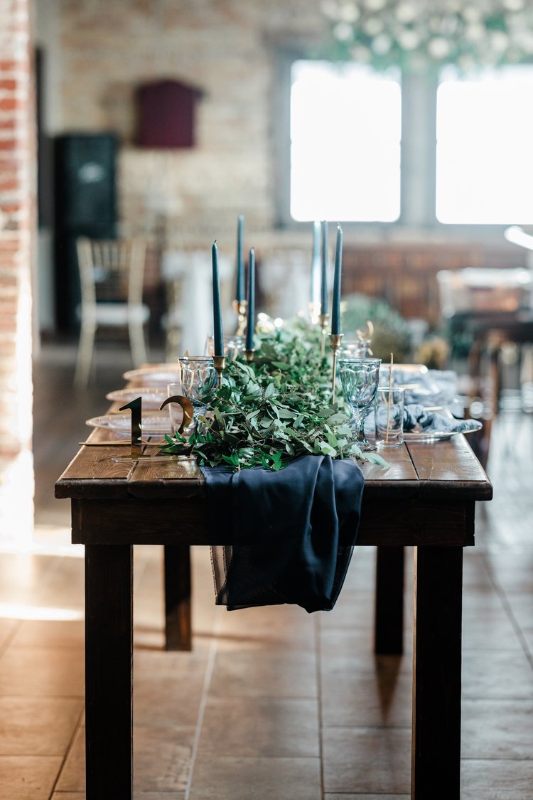 A wooden table is decorated in navy and gold for a wedding at Timekeeper Wausau Historic Depot.