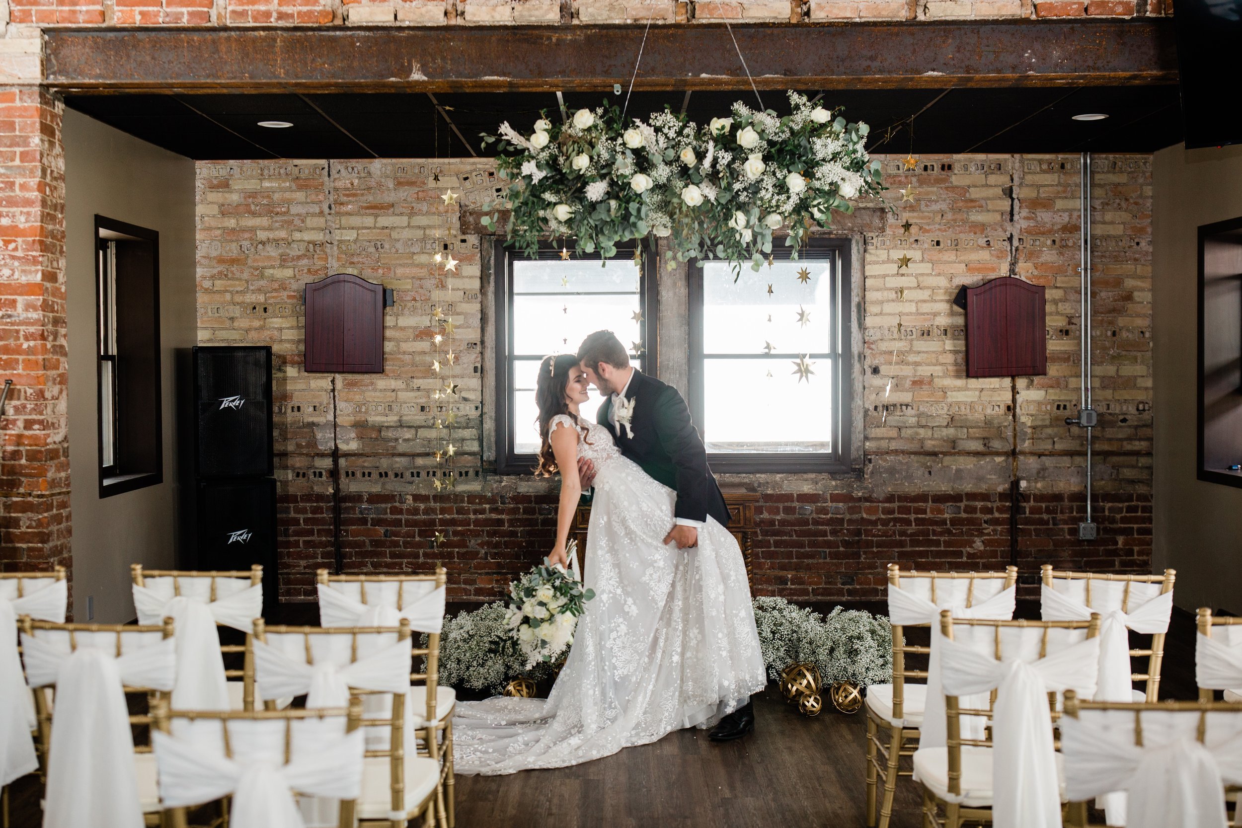 A groom dips the bride inside the beautifully the decorated Timekeeper Wausau Historic Depot.