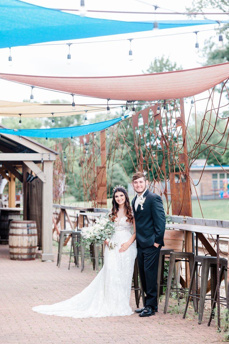 A bride and groom pose for a photo on the outdoor patio at Timekeeper Wausau Historic Depot.
