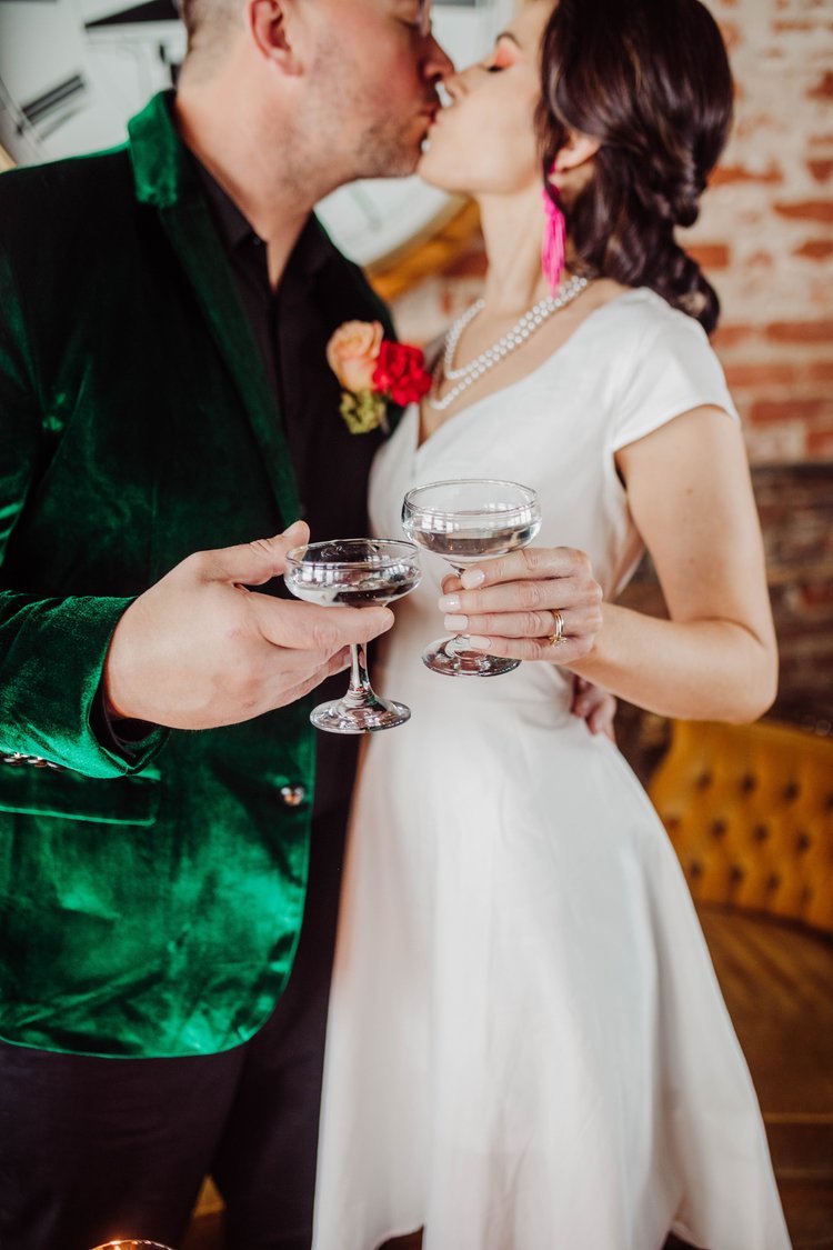 A bride and groom kiss and clink glasses during their wedding at Timekeeper's Wausau Historic Depot.