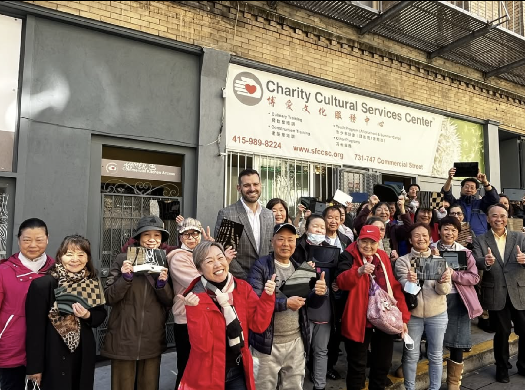 Community members standing and smiling in front of Charity Cultural Services Center office