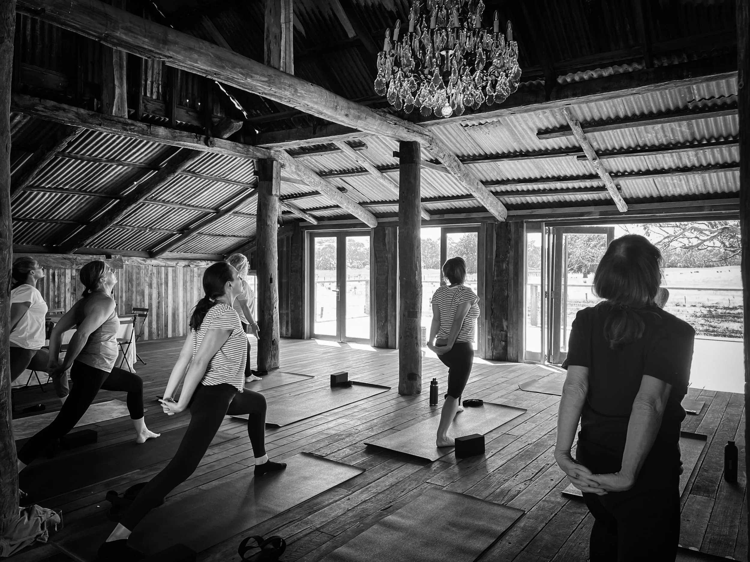 Black and white photo of a wellness retreat yoga class inside the rustic shearing shed at Dunmore.