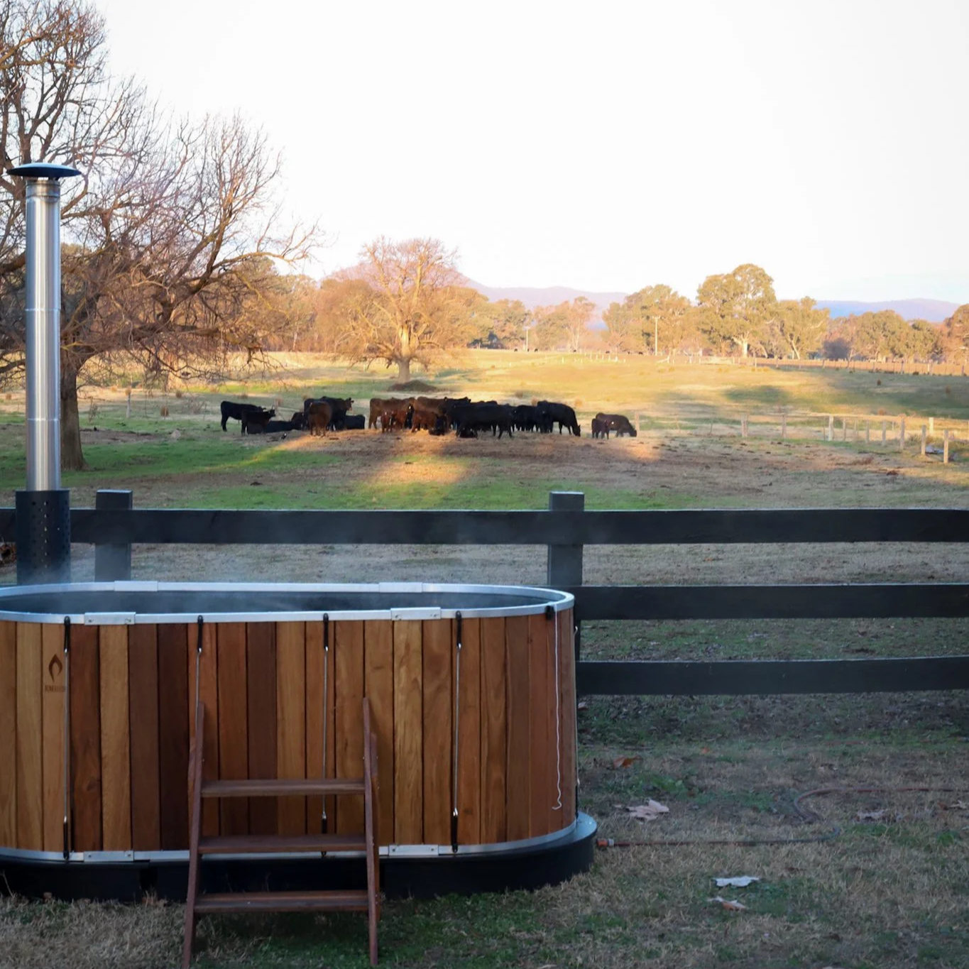Private wood-fired hot tub experience at Dunmore Farm boutique farm stay in regional Victoria with views across farmland and cattle.