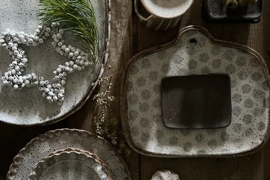 Small hand-shaped raw black ceramic plate with matte textured finish; artisan stoneware plate styled as a candle base and soap dish.