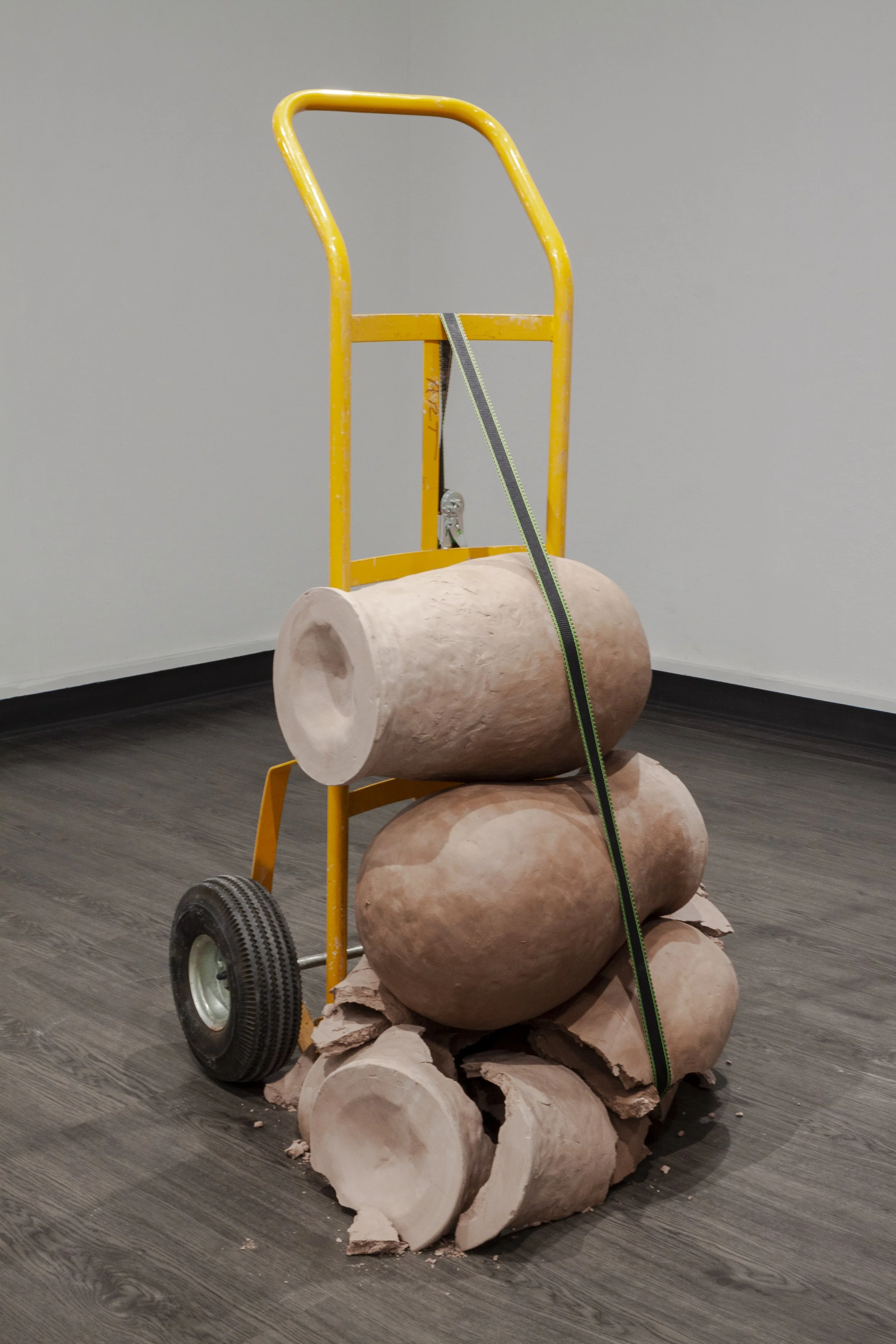    SPOILS OF THE CHURN: MOVING THE PILE or THE ONLY WAY OUT IS THROUGH      ‍  ‍  Unfired Stoneware, hand-truck, ratchet strap. 52” x 34” x 22”, 2021      