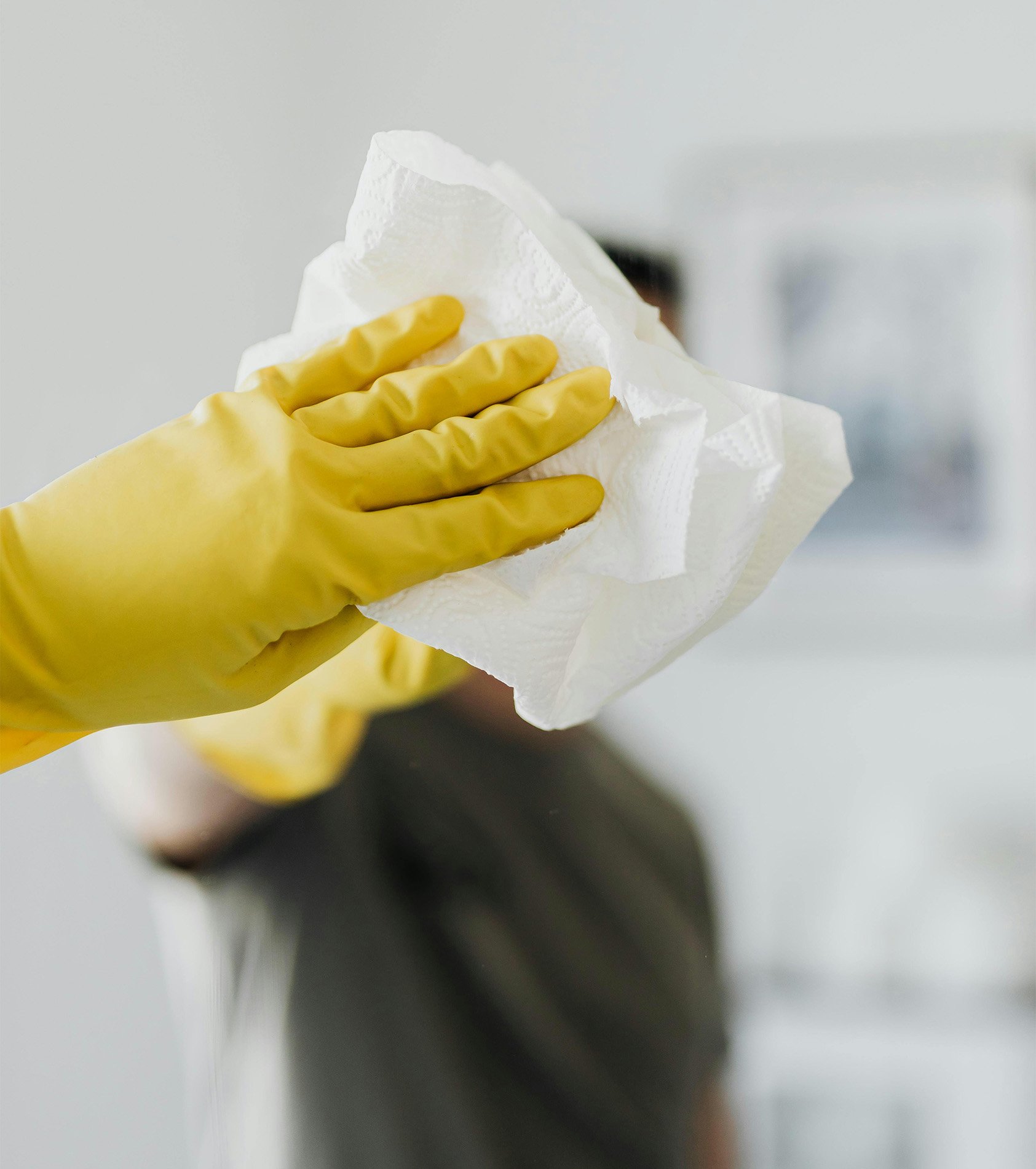 Rubber gloved hand wiping down mirror