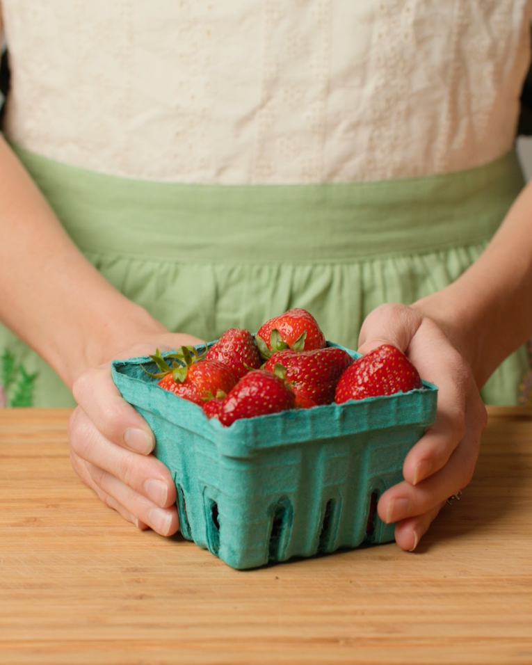fresh strawberries in a green paper crate from the farmers market