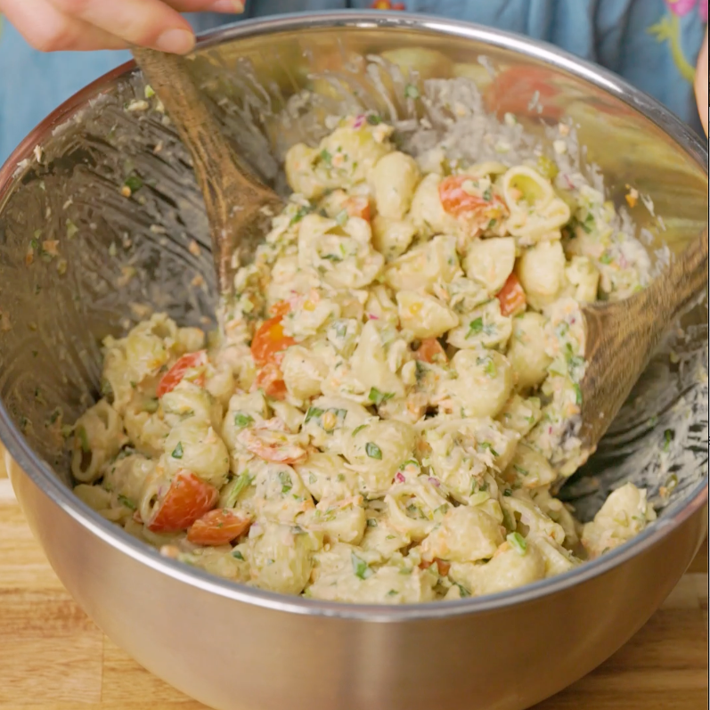 mixing pasta salad in a bowl