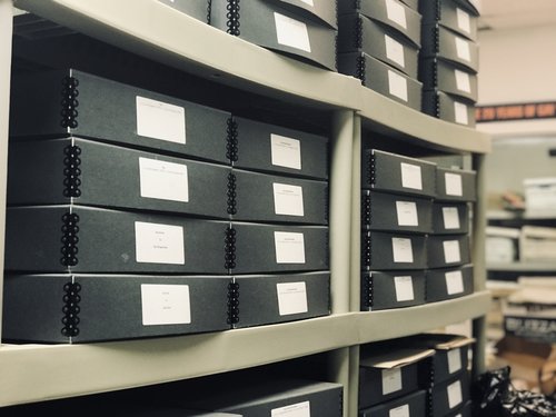 Shelving full of archive boxes with labels.