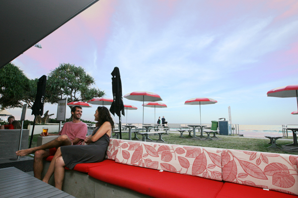 Sweeping glass sliding doors hide away into the walls to let interiors embrace the beach and surrounding public parkland, with large in-situ poured concrete bench seats forming a tangible yet activated barrier between the public zones and the licensed premises. In addition to the new bar & function room, the brief encompassed a revamp of the existing cafe kiosk, new amenities, and a small TAB and gaming room designed to operate independently should there be a function in progress. The Bluff Bar draws inspiration from the surf club’s beginnings as a traditional timber beach cottage to create a relaxed venue with warmth, character and taste. VJ wall and ceiling panels in select areas provide textural interest, coupled with the use of traditional hardwood chamfer board cladding to the main bar to provide a more domestic, beach house feel.