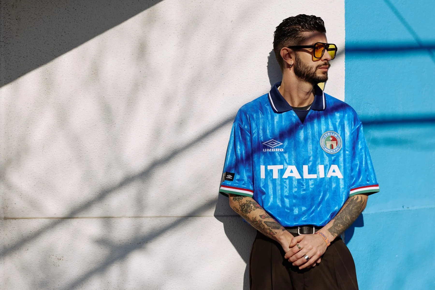 Portrait in a blue Umbro Italia football shirt against a sunlit wall