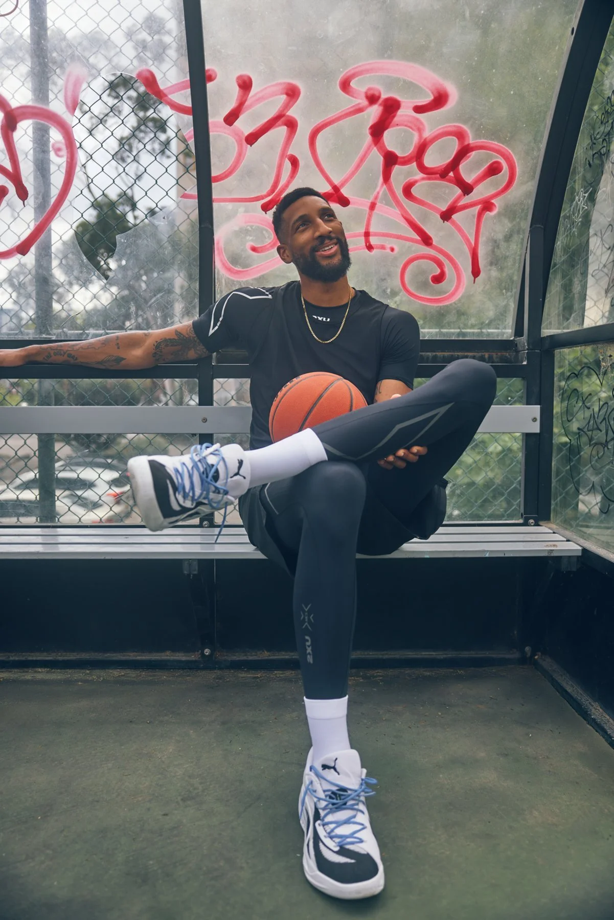 Marcus Lee seated outdoors with a basketball in 2XU sportswear