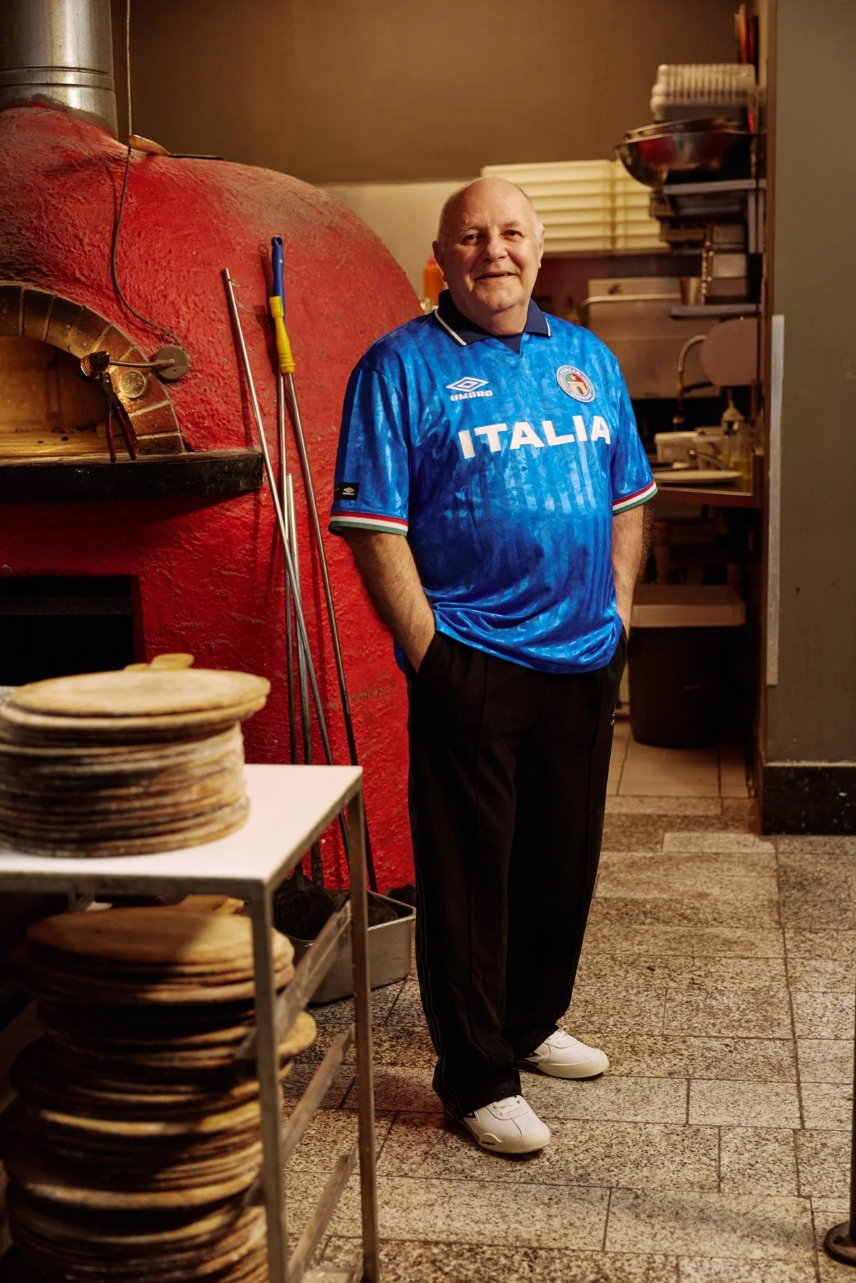 Portrait in an Umbro Italia shirt beside the pizza oven