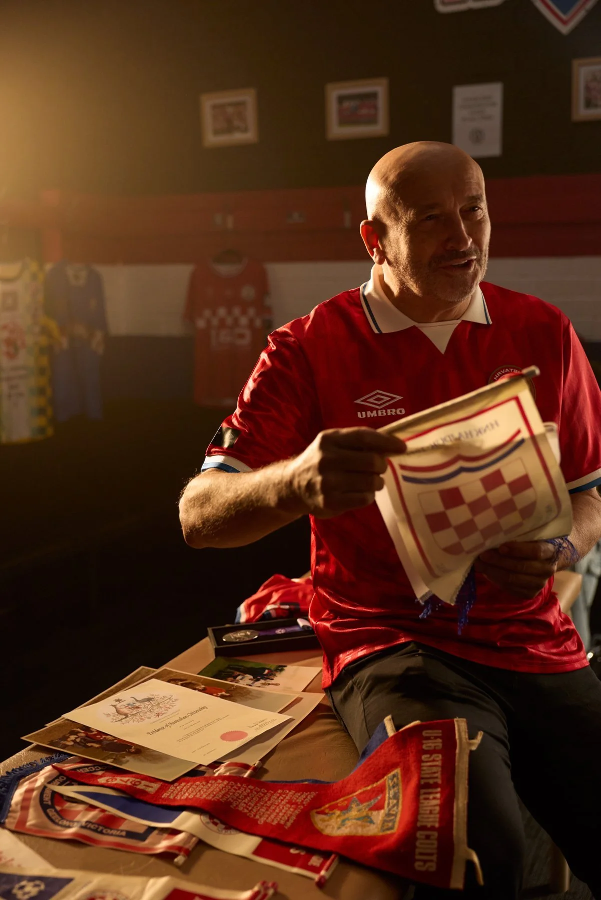 Man in a red Umbro Hrvatska shirt holding football memorabilia