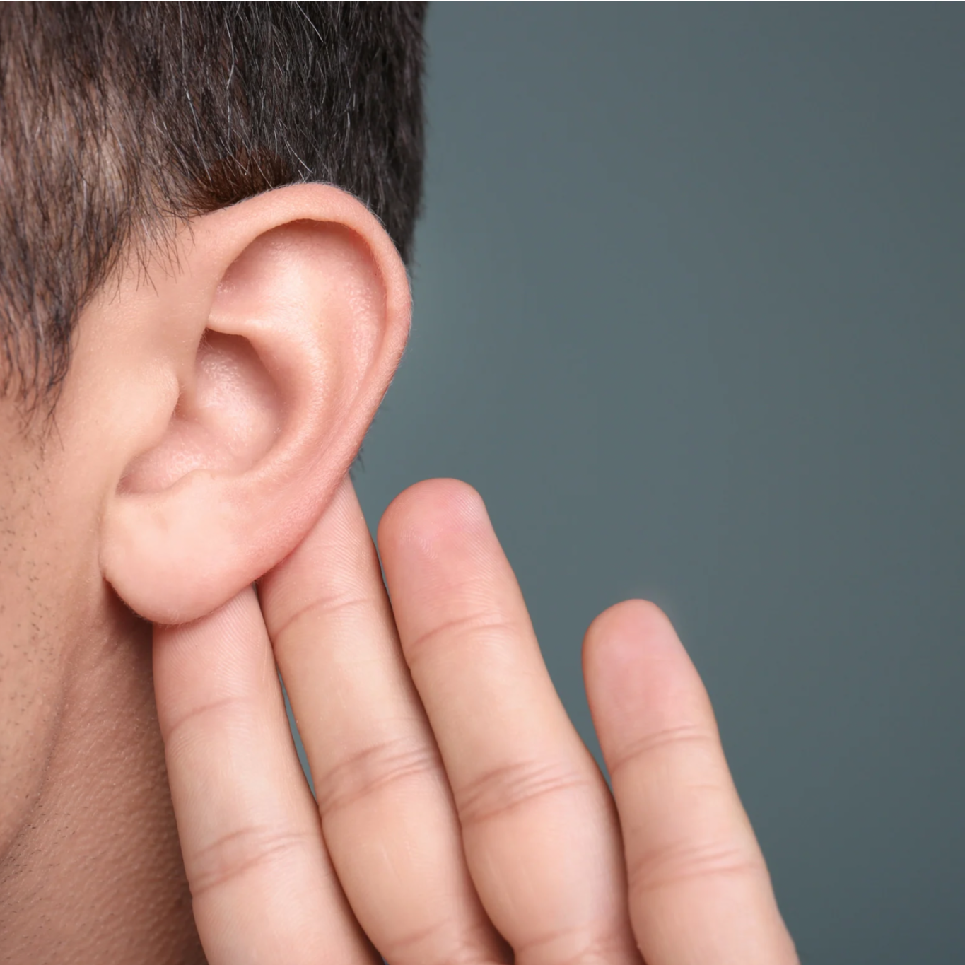 A close-up of a person's ear with fingers held near the ear, as if listening.