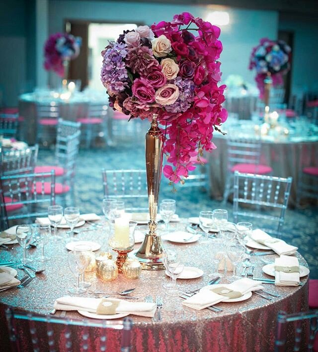 #champagne #sequintablecloth #clearchairs #icechairs #goldcandleholders #tallarrangement #weddingcenterpieces #cascading #floral #orchids #hotpink #roses #hydrangea #moodlighting
