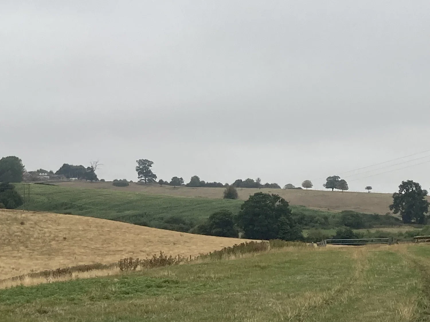 Photo of sloping fields with house on the skyline.