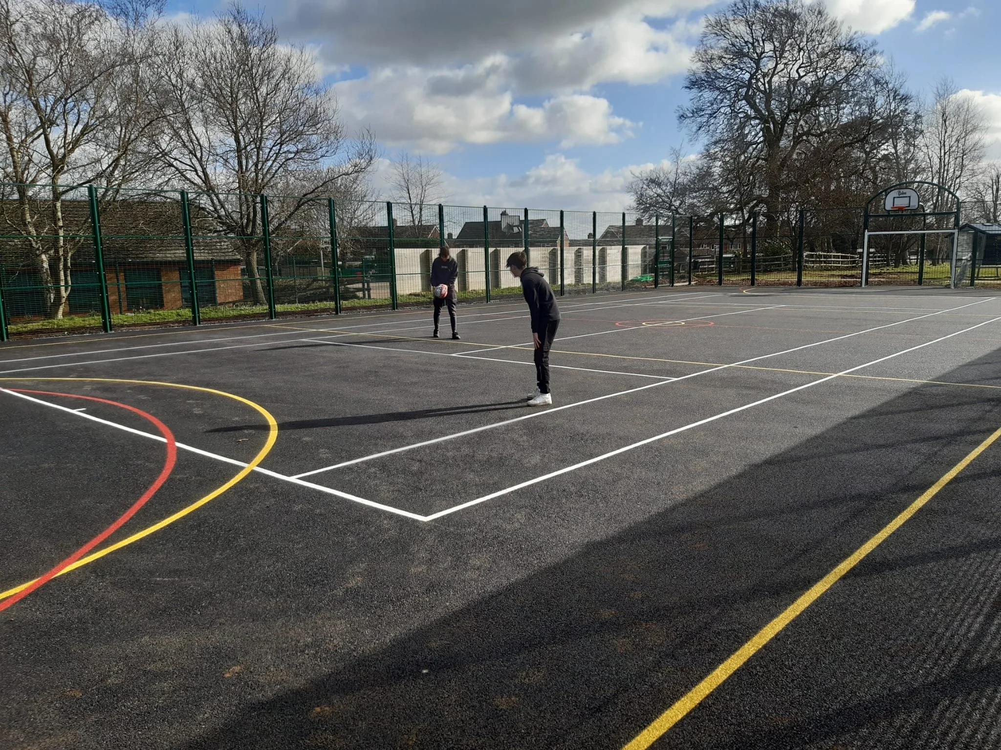 Photo of two boys with ball playing inside enclosed hard surface games area.