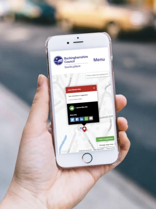 Photo of a hand holding a mobile phone displaying the  Bucks.Place app.