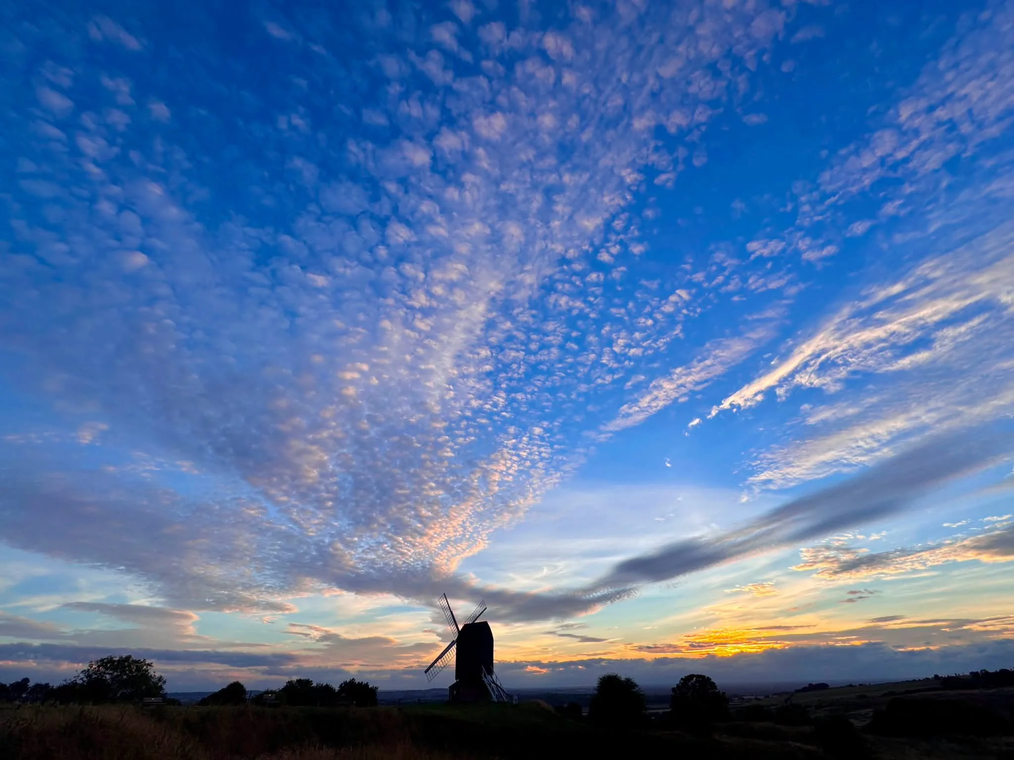 Photo of distant windmill and dramatic evening clouds