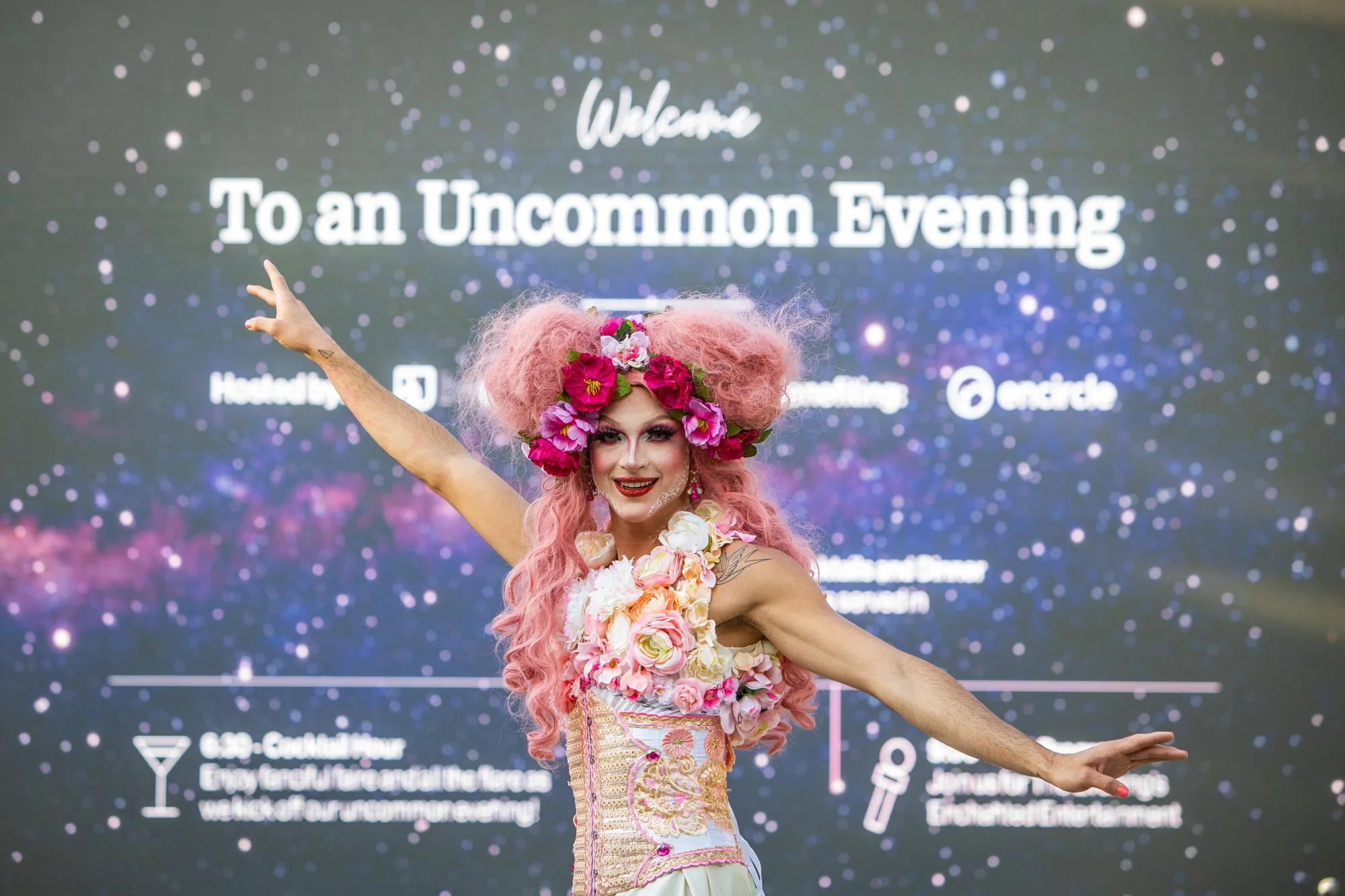 A performer on stilts in elaborate dress in front of a LED Screen at a charity gala in Denver, Colorado