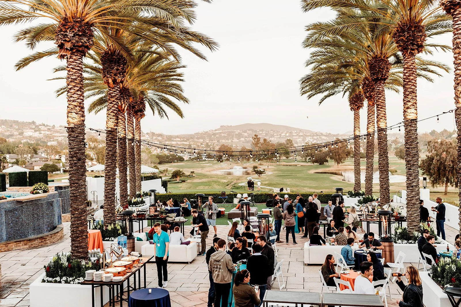 Corporate Destination Event Guests on Veranda under palm trees and string lights overlooking a mountain in Carlsbad, California