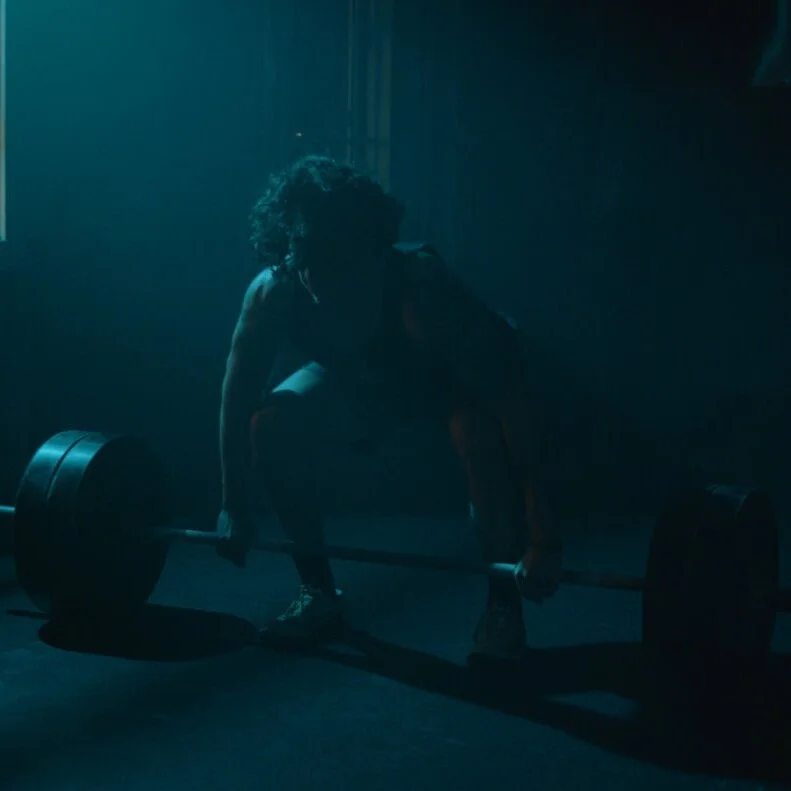 Athlete preparing to lift a barbell in a dark gym setting from the “Find Your Strength” brand commercial, produced by Killshot Media.