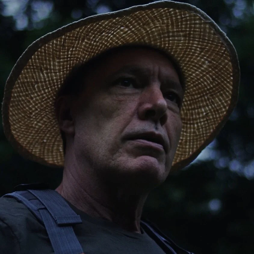 Man wearing a straw hat standing outdoors in a wooded area from the “Marketing Dollars” commercial, produced by Killshot Media.