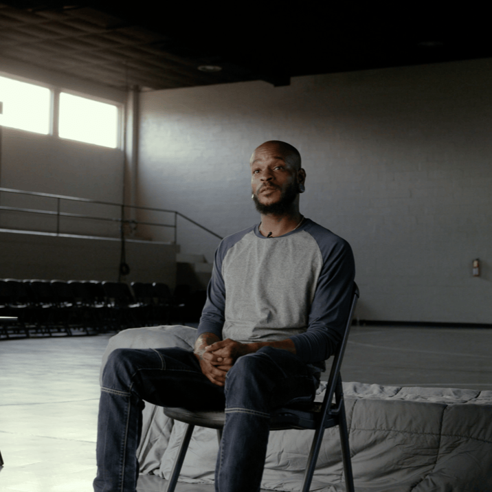 Man seated in a studio setting during an interview for a documentary film.