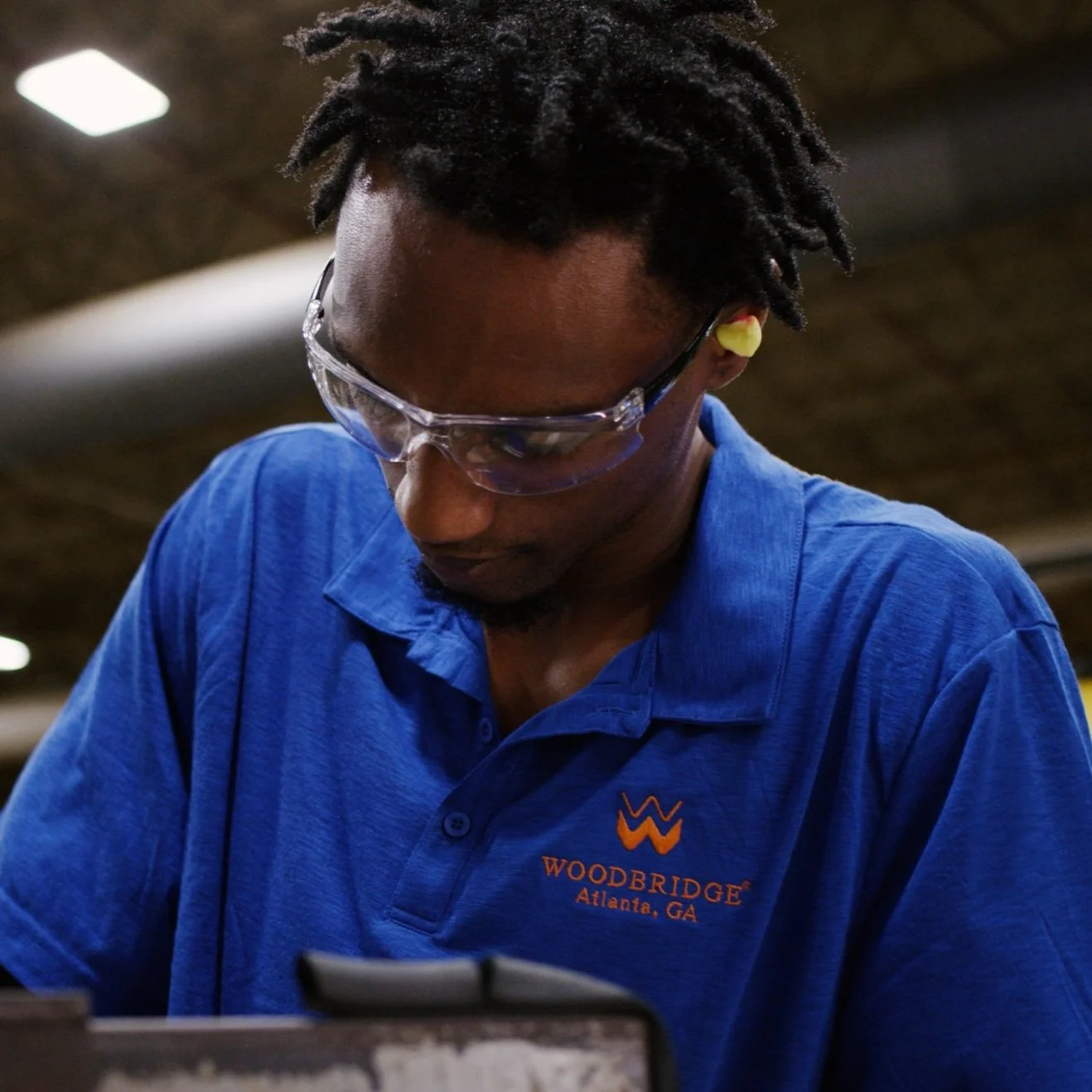 Factory worker operating equipment on a manufacturing floor for Woodbridge Group.