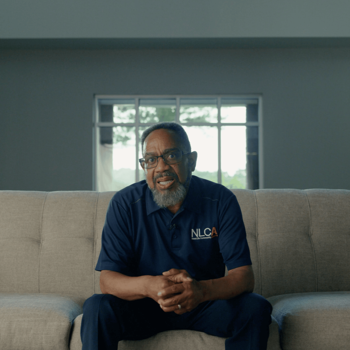 Man speaking on camera in a living room setting for a nonprofit story video.
