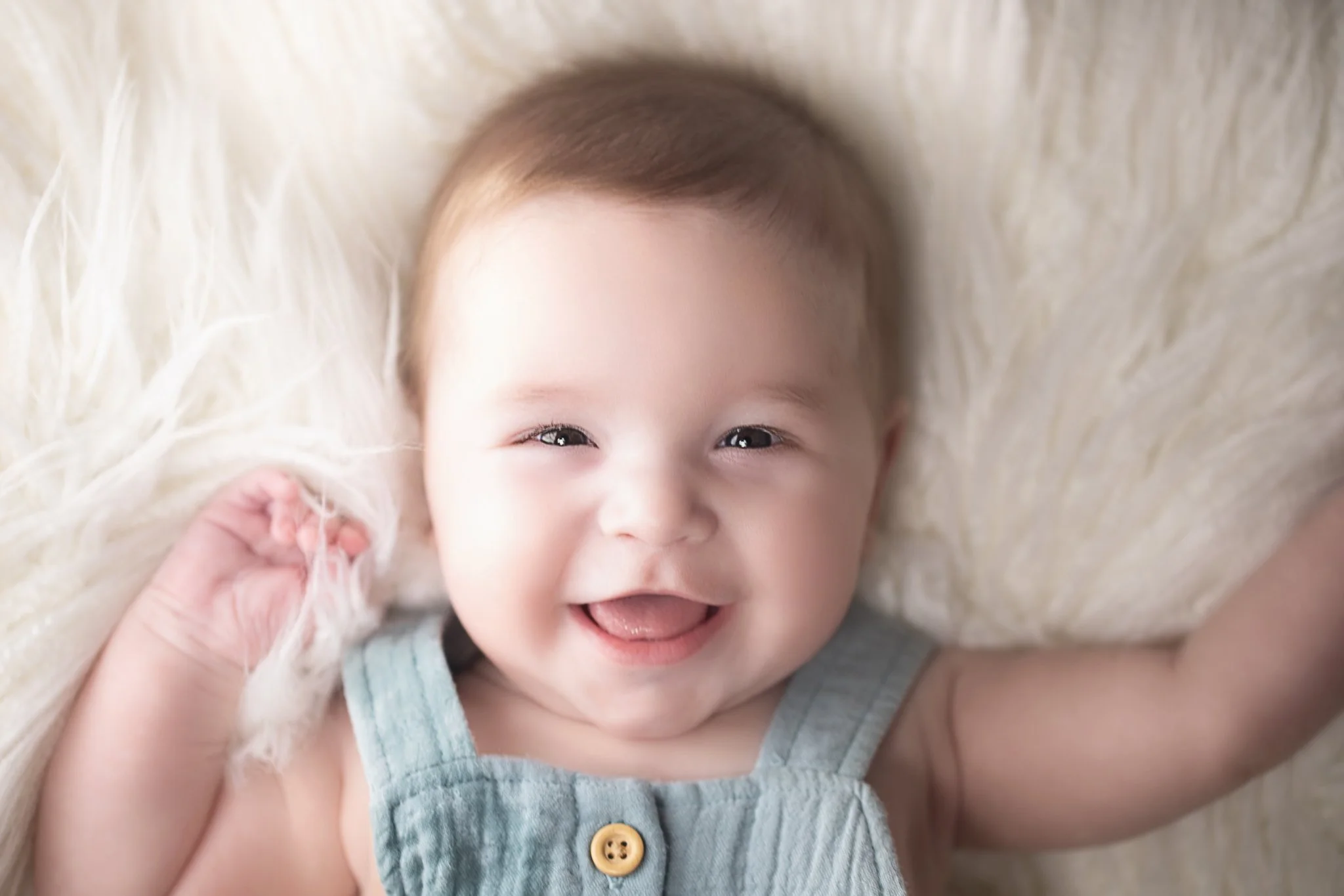 Close-up of a smiling baby lying on a soft, fluffy blanket.