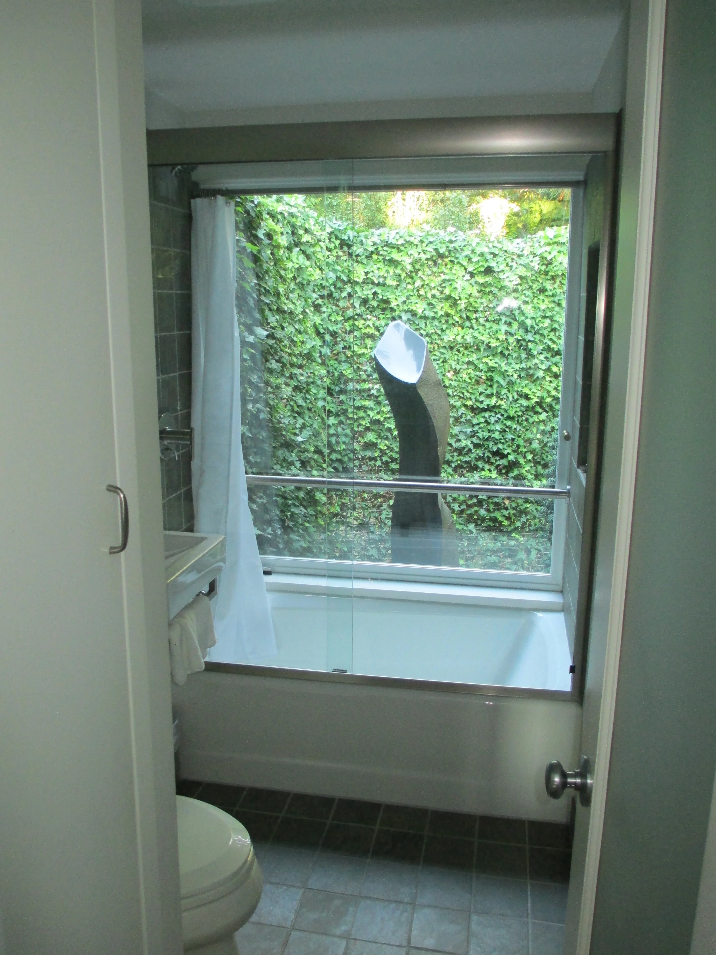 Bathroom window wall installed at tub to capture private exterior sculpture garden.