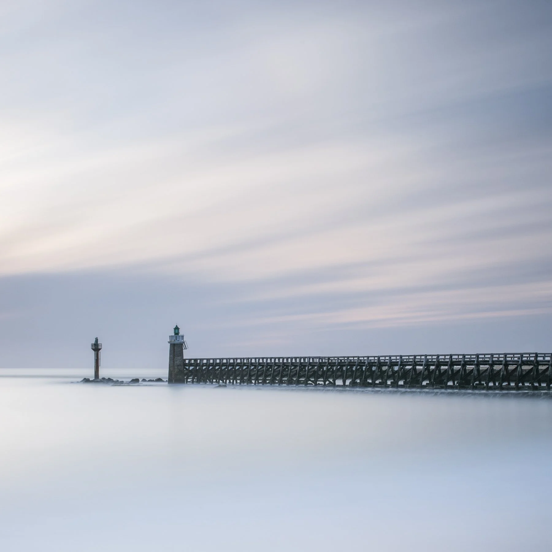 Capbreton. Pier in summer in soft dawn light, long exposure and still sea in France.