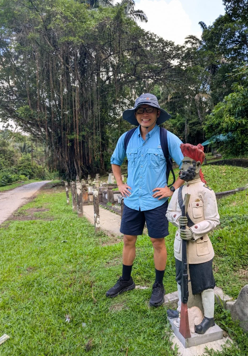 Singapore guide Gee Soo standing beside a traditional cemetery statue at Bukit Brown Cemetery