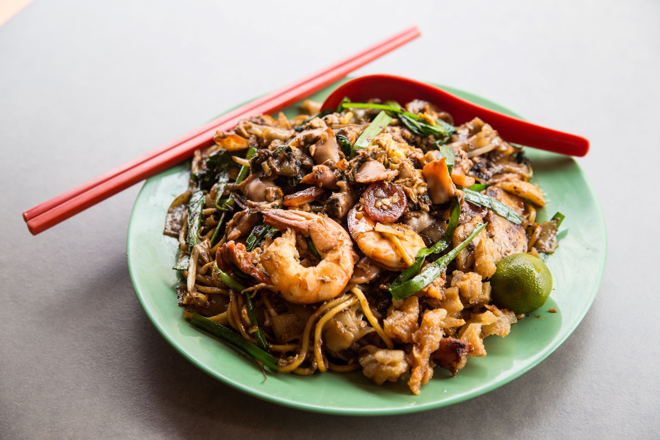 A plate of fried kway teow with spoon and chopstick.jpg