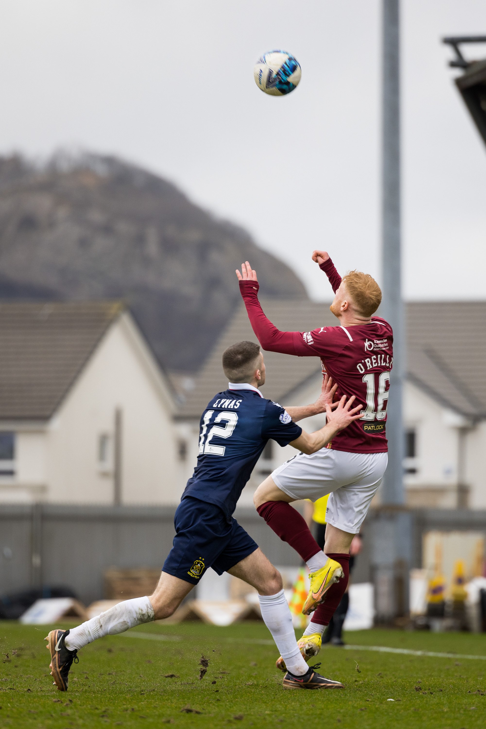  Euan O’Reilly is pushed by a Dumbarton player while rising for a header 