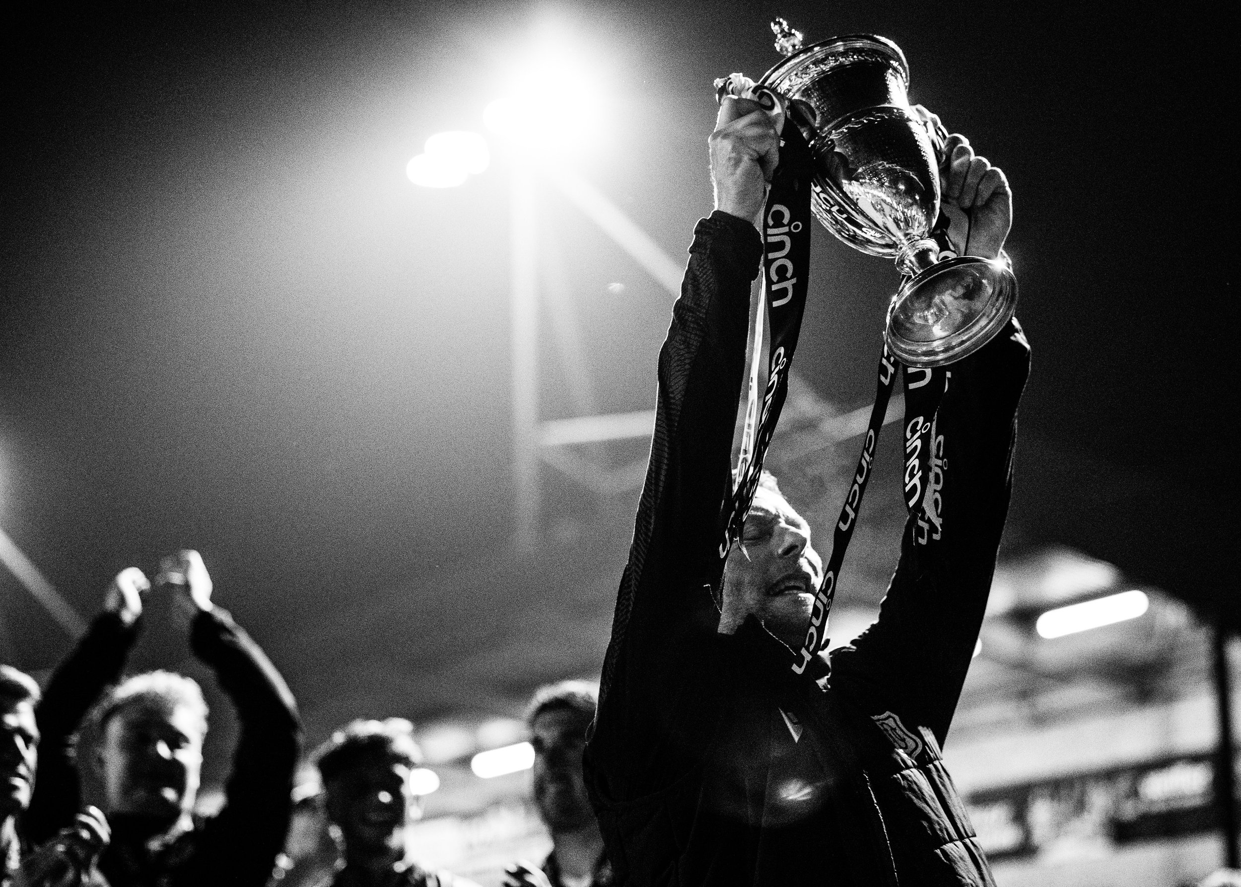  Black and white image of Dundee staff lifting the Championship trophy in 2023 