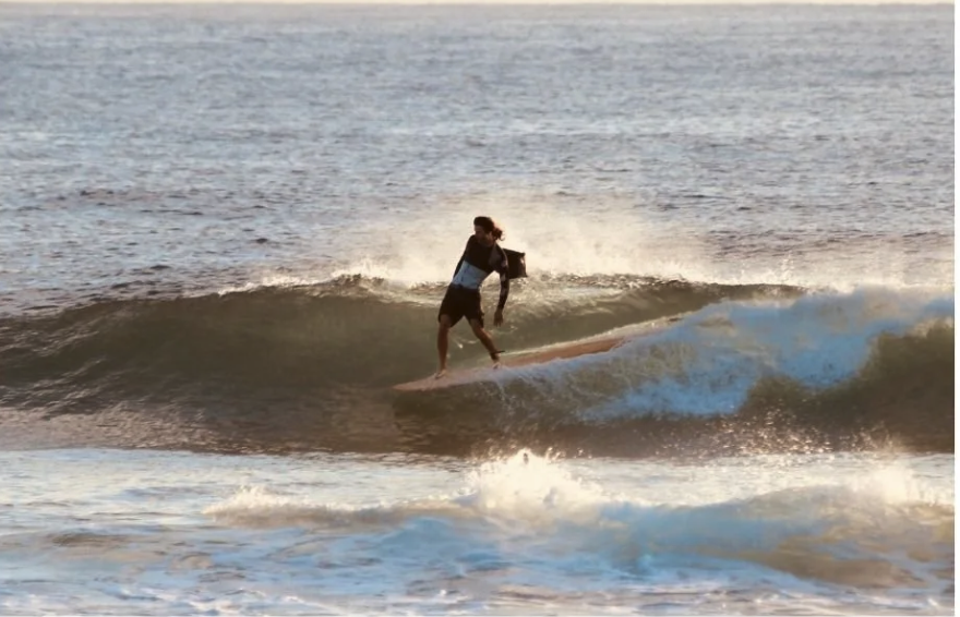 A person surfing on a small wave near the shoreline.