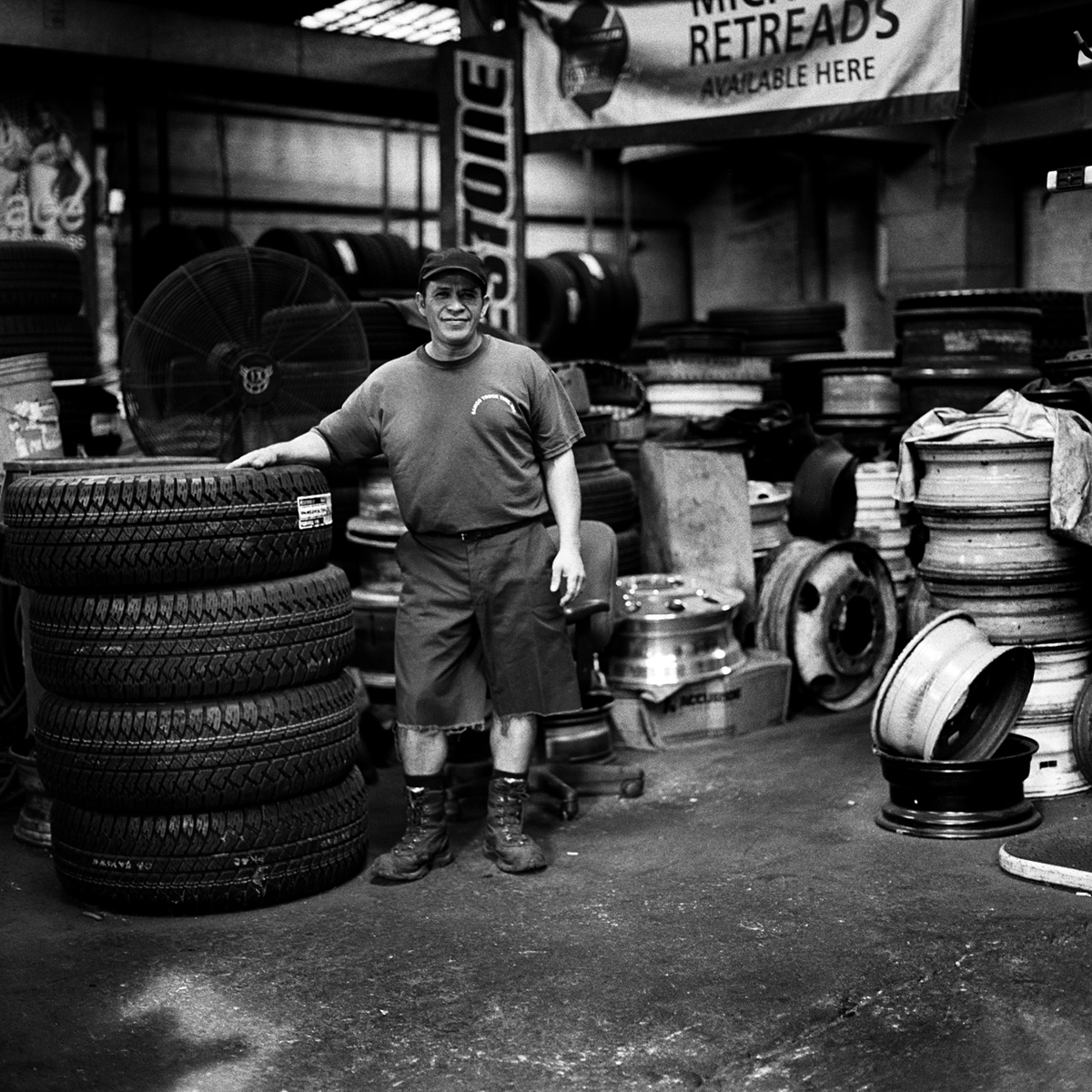  Samco Truck Tire employee, Hector, stands before the valley of tires used to service the hundreds of trucks that criss-cross the industrial zone that resonates from the banks of Newtown Creek.  Bushwick, Brooklyn, N.Y. (Oct. 2015) 