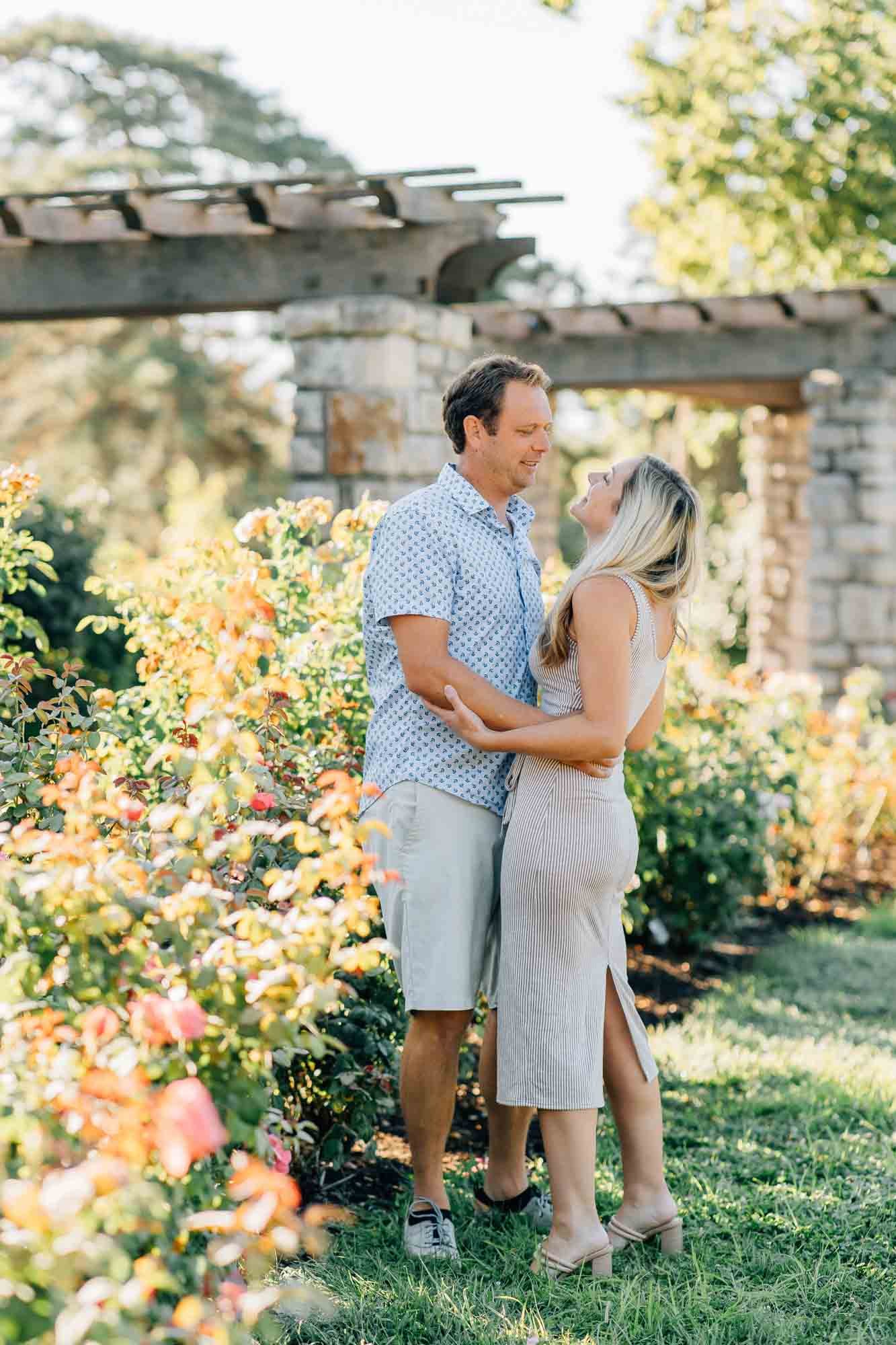 husband and wife embracing in rose garden
