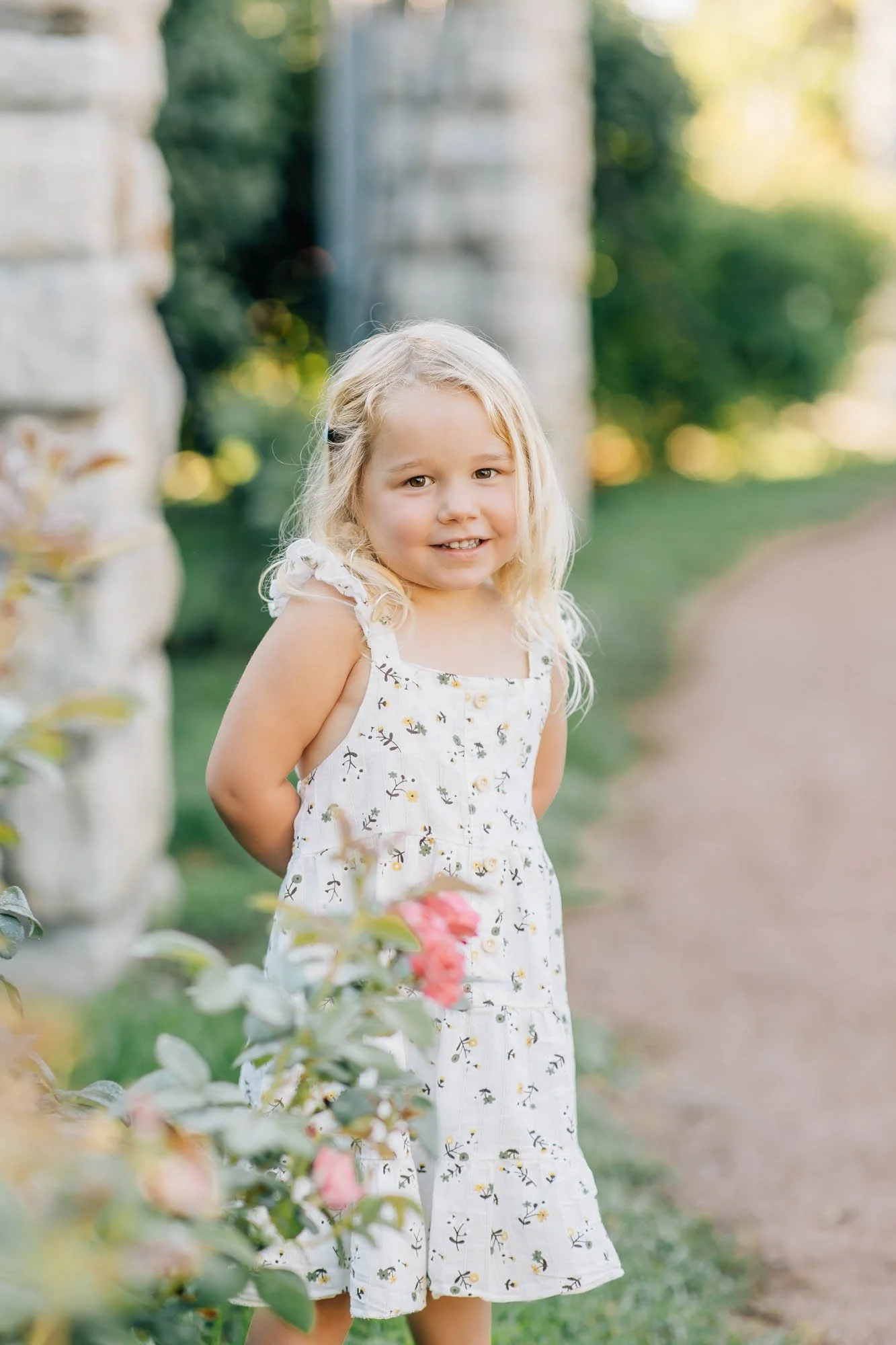 little girl smiling and posing in a rose garden