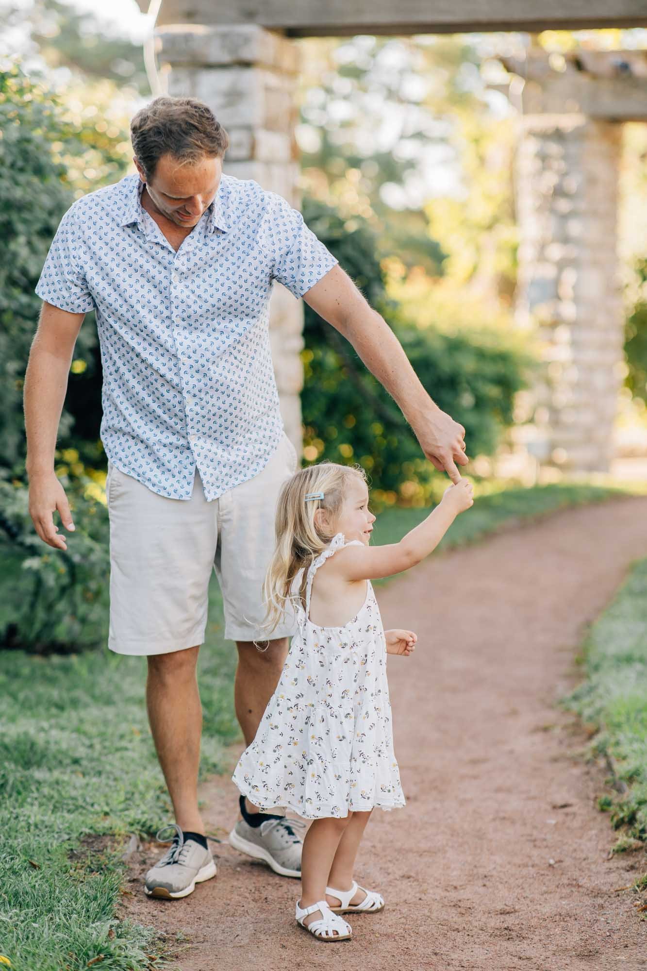 Father and daughter walking hand in hand on garden path, Loose Park Rose Garden family session Kansas City
