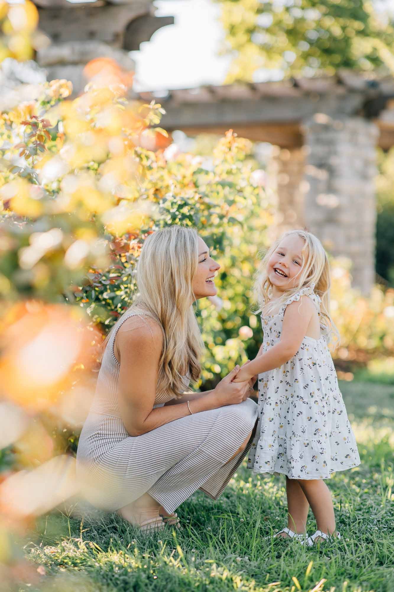 mother kneeling down to talk to her young daughter in the rose garden