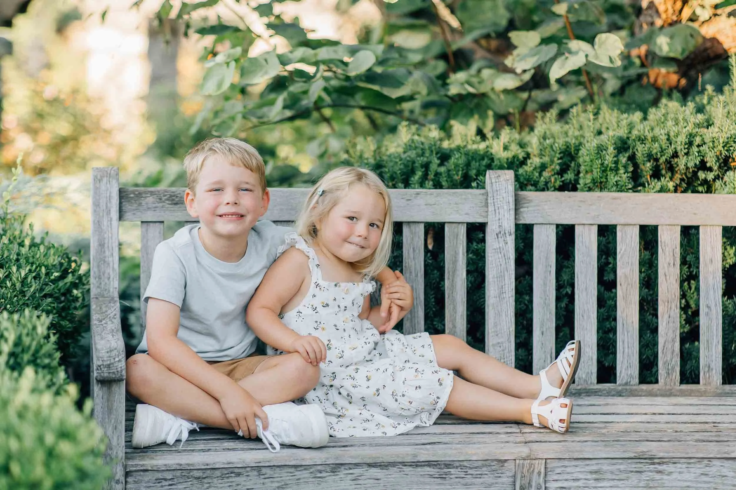two young kids smiling and sitting on a bench in Loose Park Kansas City